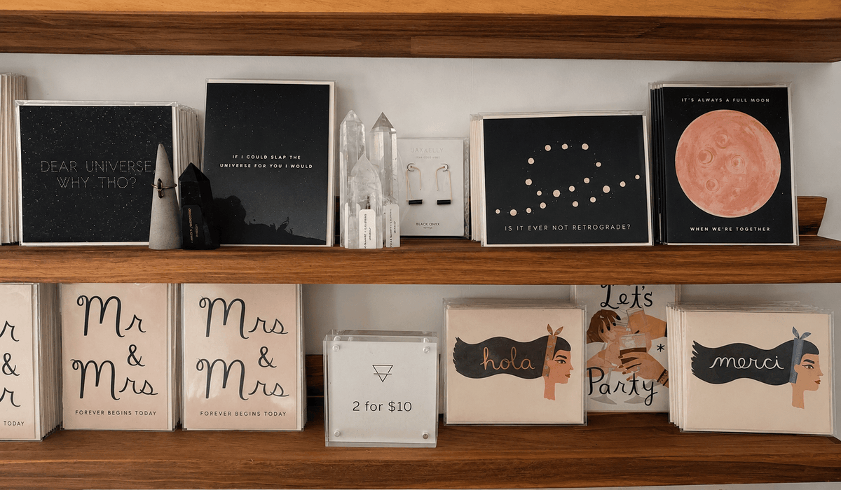 Greeting cards, books, and framed artwork arranged on a wooden shelf at Grounded Bodyworks.