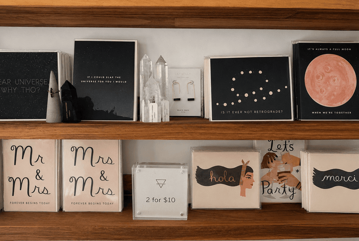 Greeting cards, books, and framed artwork arranged on a wooden shelf at Grounded Bodyworks.