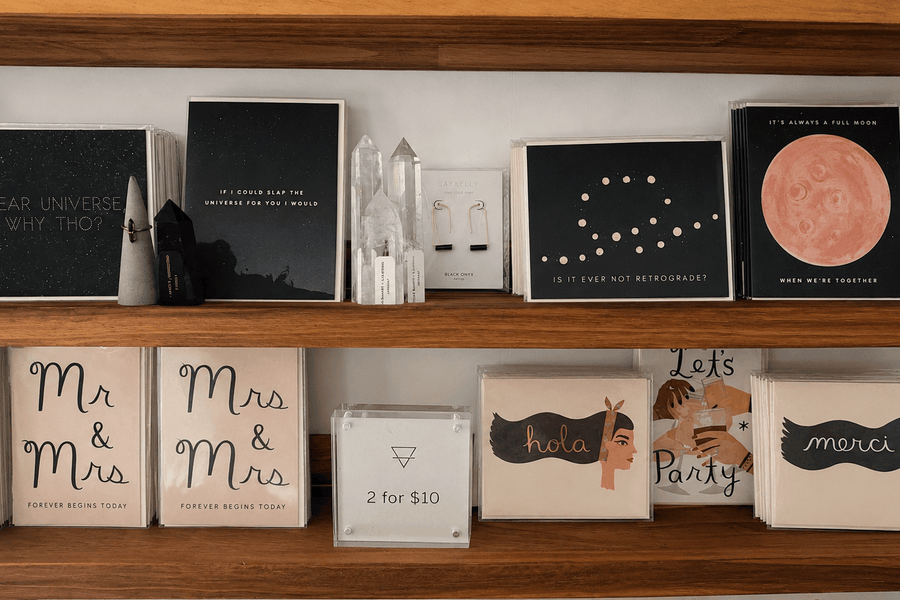 Greeting cards, books, and framed artwork arranged on a wooden shelf at Grounded Bodyworks.